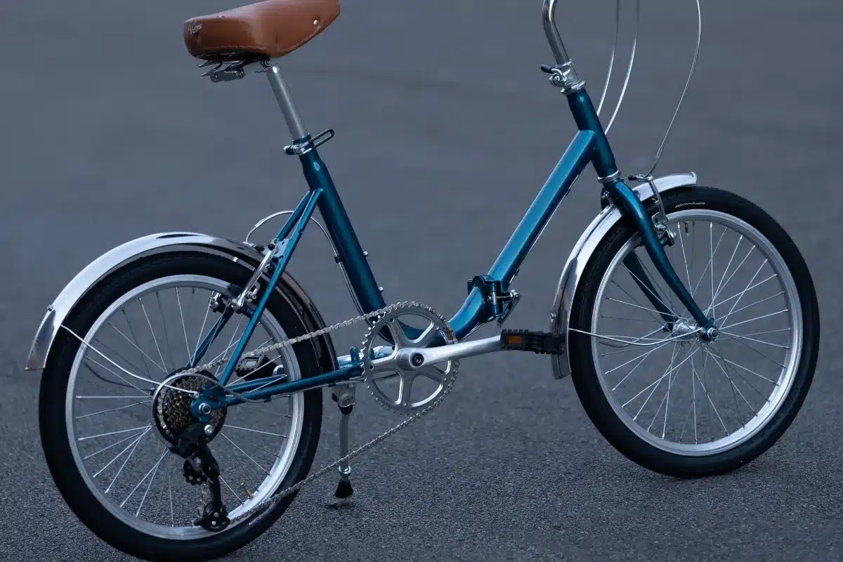 Seitenansicht eines blauen Capri Vita Falt-E-Bikes mit braunem Sattel und 20-Zoll-Rädern.