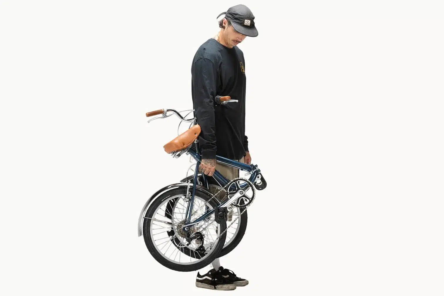 Mann trägt ein blaues Capri Vita Falt-E-Bike mit braunem Sattel, Vorderansicht.