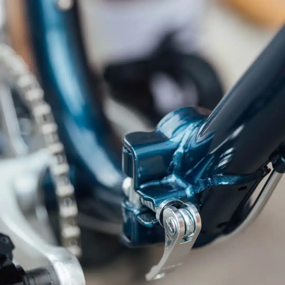 Nahaufnahme des blauen Stahlrahmens eines Capri Vita Falt-E-Bikes, Fokus auf den Schnellspanner-Mechanismus.