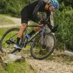 Radsportler fährt mit einem Giant Charge Pro MTB über einen unbefestigten Weg im Wald, umgeben von Bäumen und Grün.