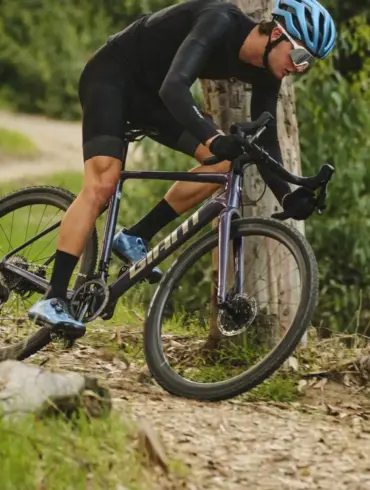 Radsportler fährt mit einem Giant Charge Pro MTB über einen unbefestigten Weg im Wald, umgeben von Bäumen und Grün.