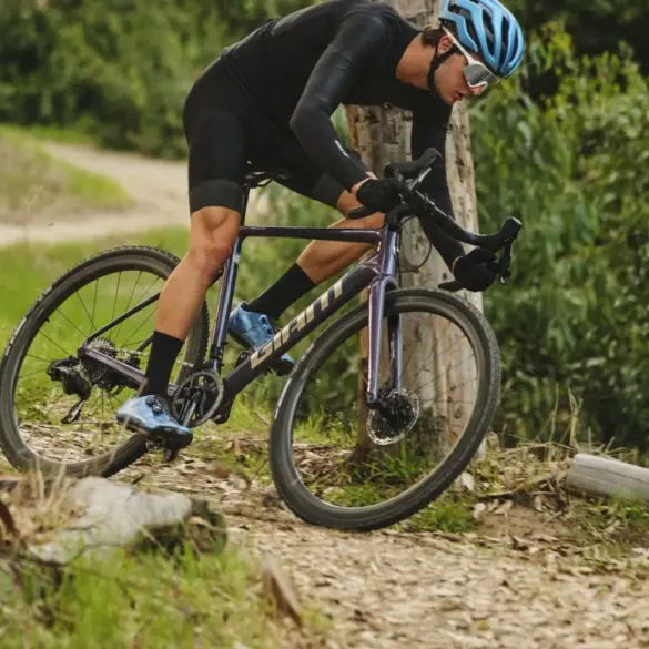 Radsportler fährt mit einem Giant Charge Pro MTB über einen unbefestigten Weg im Wald, umgeben von Bäumen und Grün.