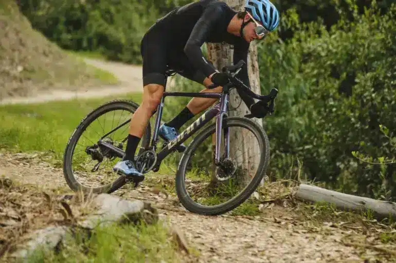 Radsportler fährt mit einem Giant Charge Pro MTB über einen unbefestigten Weg im Wald, umgeben von Bäumen und Grün.