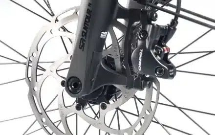 Detail der vorderen Scheibenbremse eines Fahrrads mit integrierter Federgabel, zeigt die Tektro-Bremse und die SR Suntour Gabel.