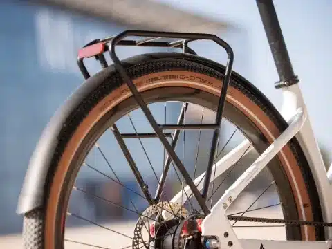 Hinterrad eines BULLS Sturmvogel EVO E-Bikes mit Schwalbe G-One Reifen, schwarzem Gepäckträger und Rücklicht. Detailaufnahme des Rahmens und des Antriebsriemens.