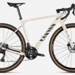 Canyon Grizl AL 7 Gravel-Bike in heller Sandfarbe mit schwarzen Akzenten, ausgestattet mit DT Swiss Laufrädern und Schwalbe G-One Reifen.