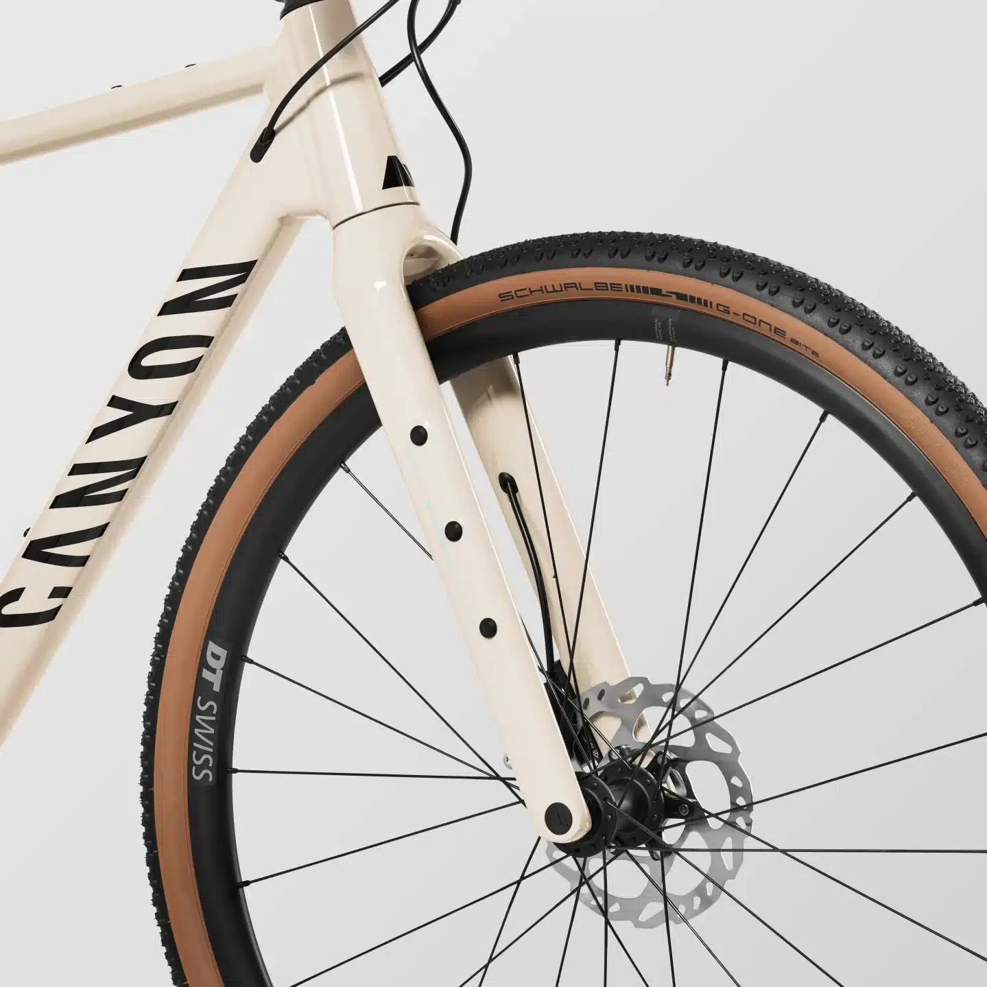 Detailaufnahme des beigefarbenen Aluminiumrahmens und der Carbongabel eines Canyon Grizl AL 7 Gravel Bikes mit Schwalbe G-One Bite Reifen auf DT Swiss Laufrad.