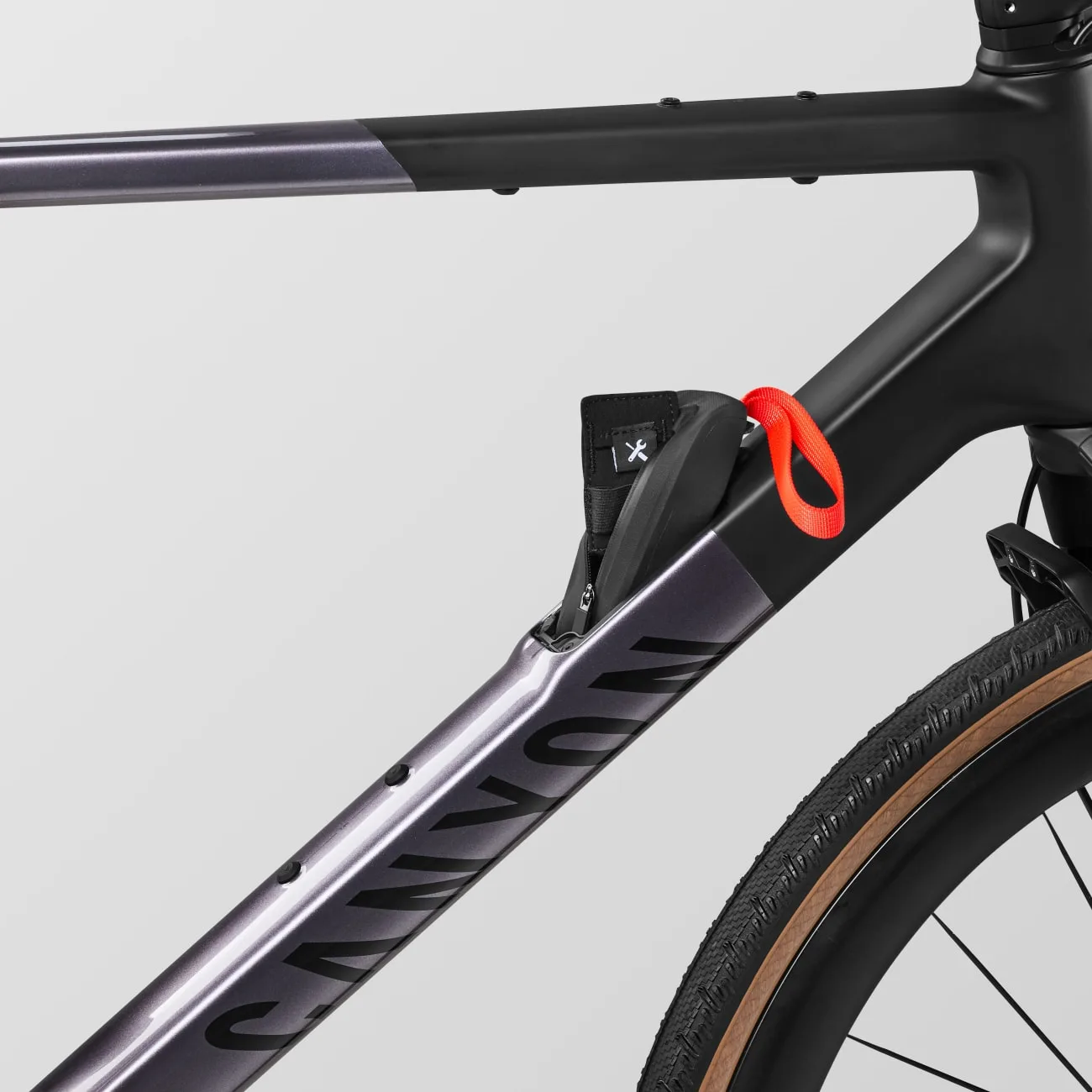 Detailansicht des Rahmens eines Canyon Grail CF SLX 8 w/ RIFT Gravelbikes, das eine integrierte Tasche mit einem Werkzeugsymbol und einer roten Schlaufe zeigt.