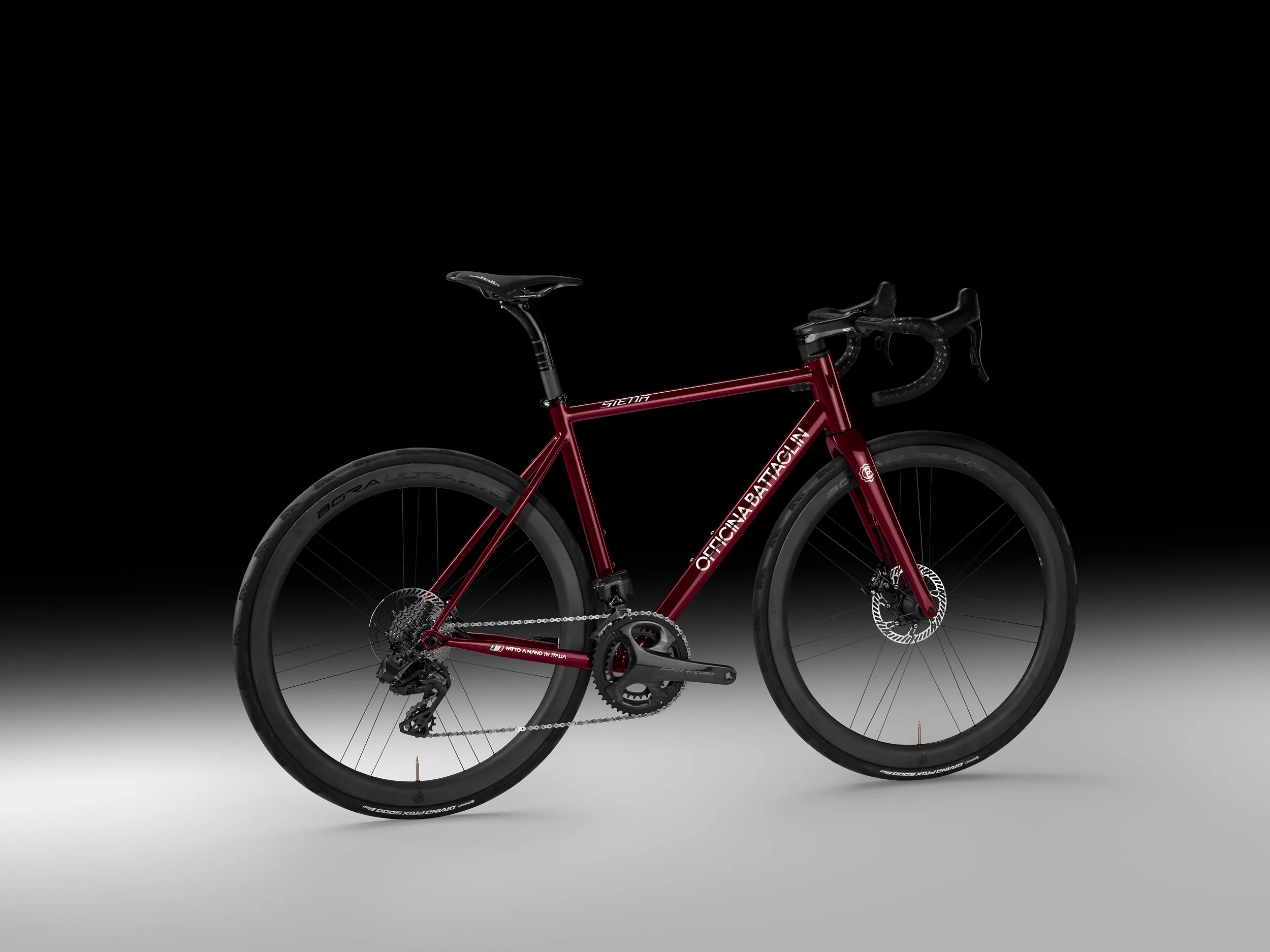 Rotes Officina Battaglin Siena Rennrad in einer Seitenansicht mit dunklem Hintergrund.