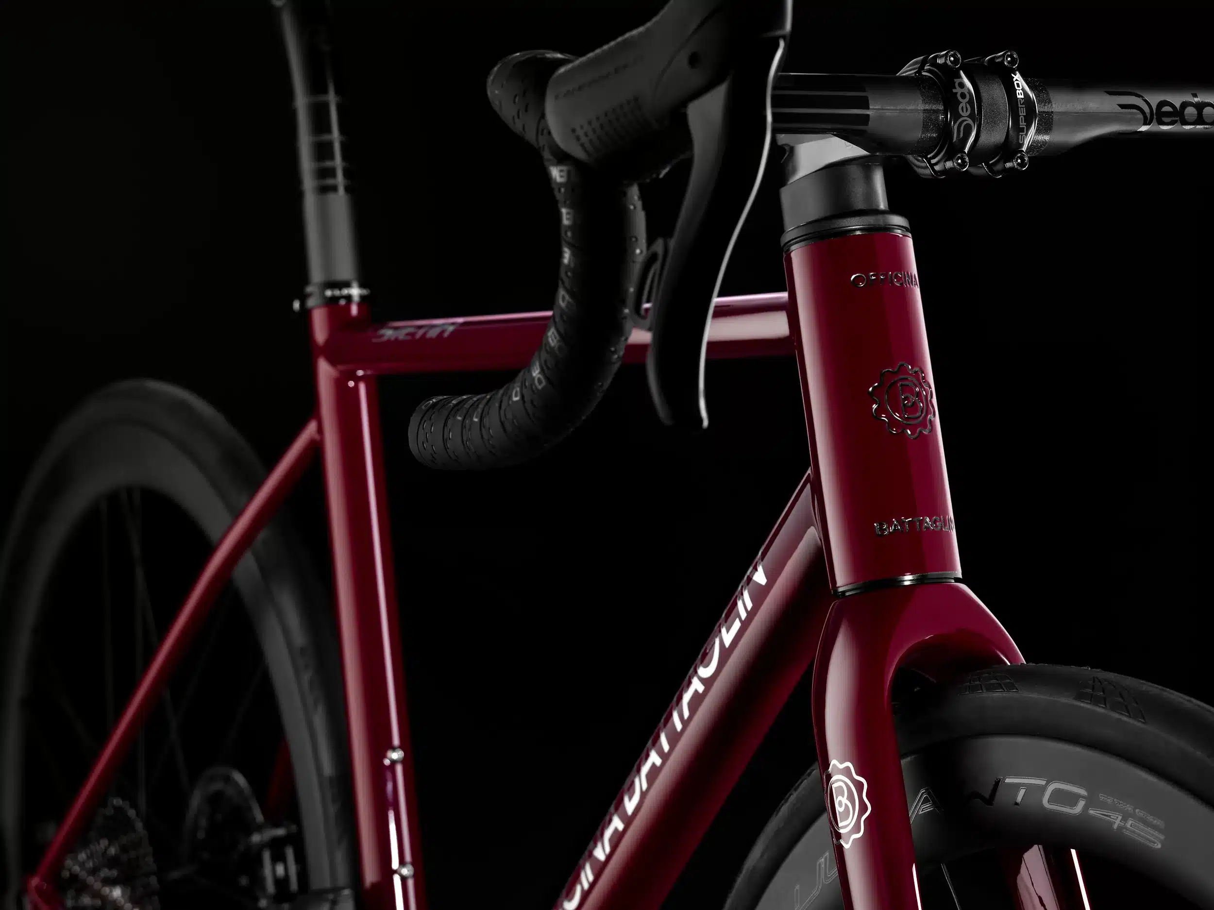 Dunkelrotes Officina Battaglin Siena Rennrad im Detail, Fokus auf das Oberrohr mit dem Schriftzug 'Siena' und das Steuerrohr mit dem Battaglin-Logo.