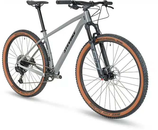 Ein graues Stevens Sonora Carbon Hardtail Mountainbike mit braunen Reifen, gezeigt von vorne links.