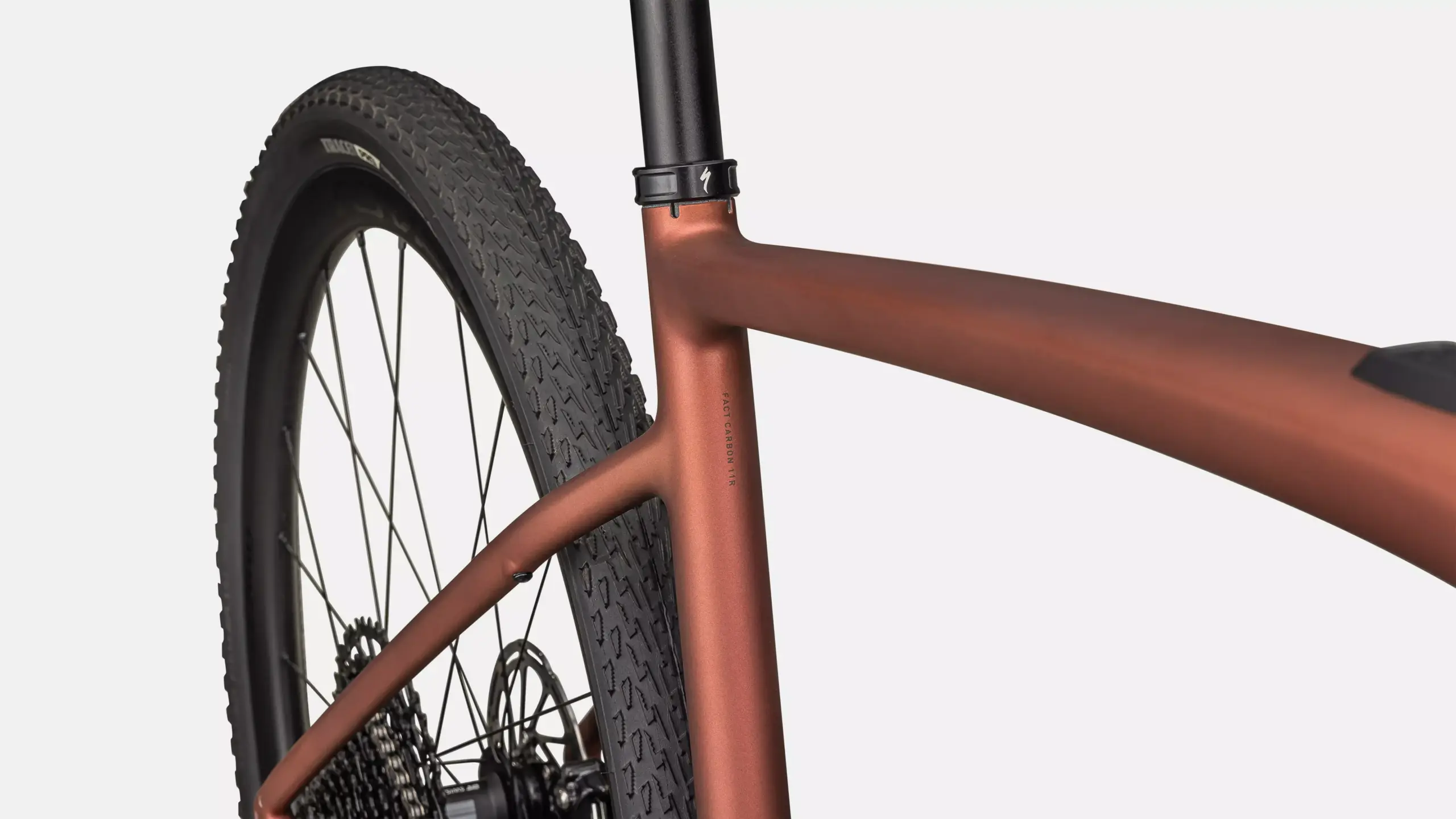Detailansicht eines bronzefarbenen Specialized Turbo Creo 2 Expert E-Gravelbikes, Fokus auf den Carbonrahmen und das Hinterrad mit grobstolligem Reifen.