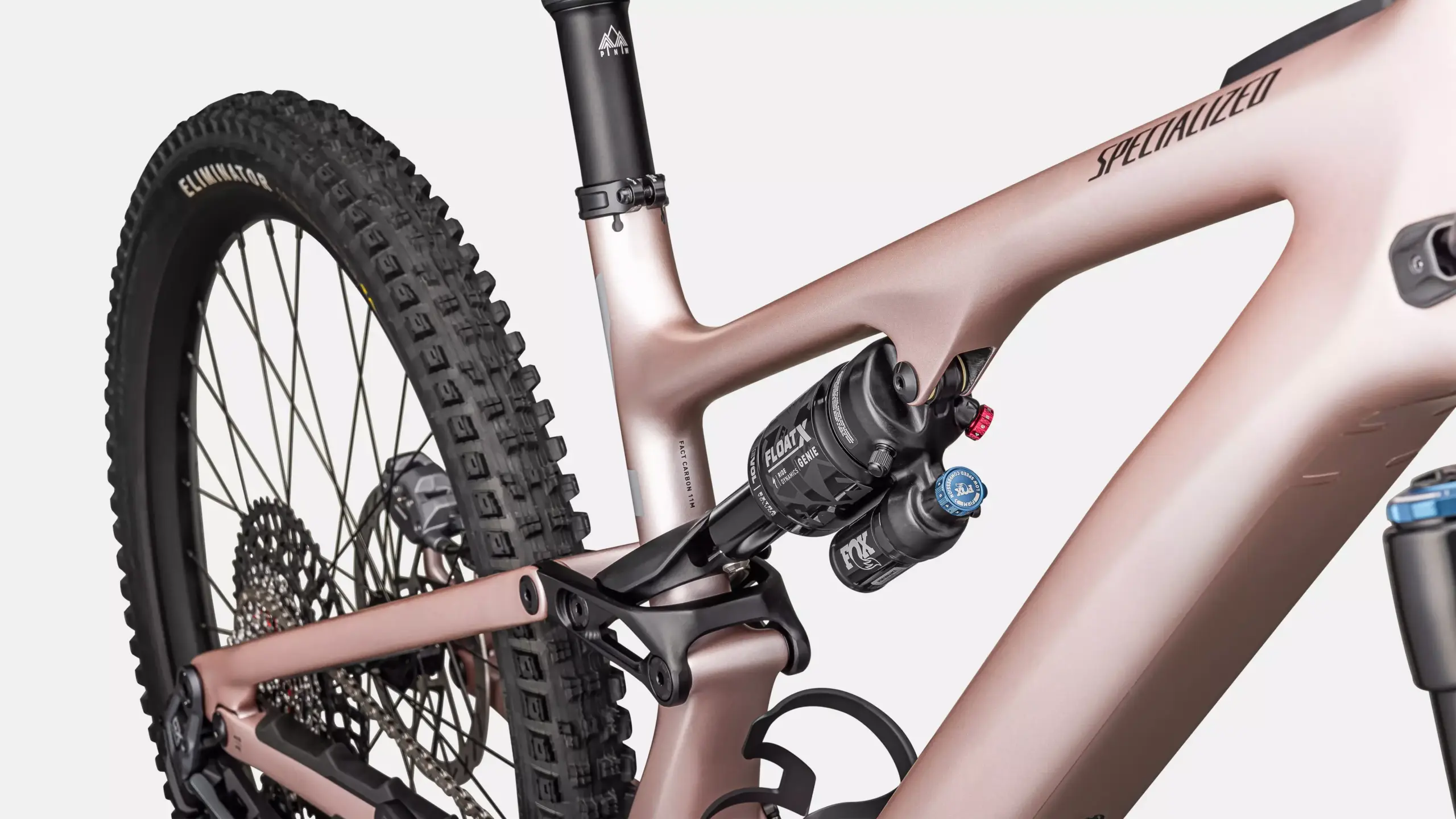 Detailaufnahme des Hinterbaus eines rosafarbenen Specialized Turbo Levo SL 2 Expert E-Mountainbikes mit Fokus auf den Fox Float X Dämpfer mit GENIE-Technologie und den FACT Carbon 11m Rahmen.