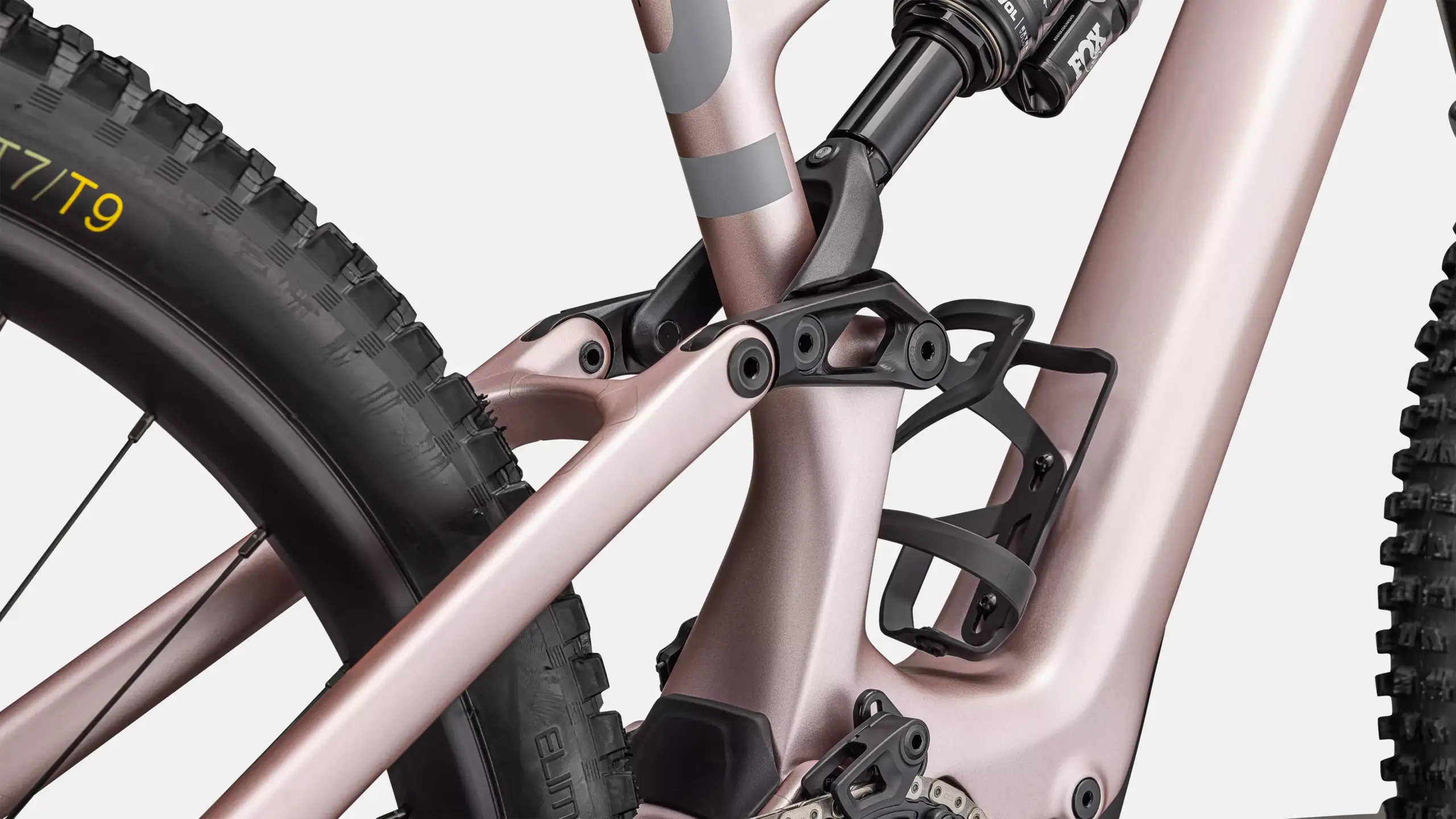 Nahaufnahme des Hinterbaus eines rosegoldfarbenen Specialized Turbo Levo SL 2 Expert E-Mountainbikes mit Fox-Dämpfer und Reifenprofil