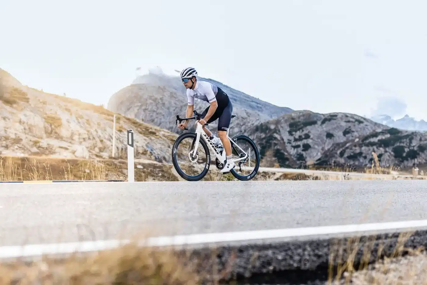 Rennradfahrer auf einem Stevens Arcalis Rennrad, das mit Scheibenbremsen ausgestattet ist, fährt auf einer asphaltierten Straße in einer bergigen Landschaft.