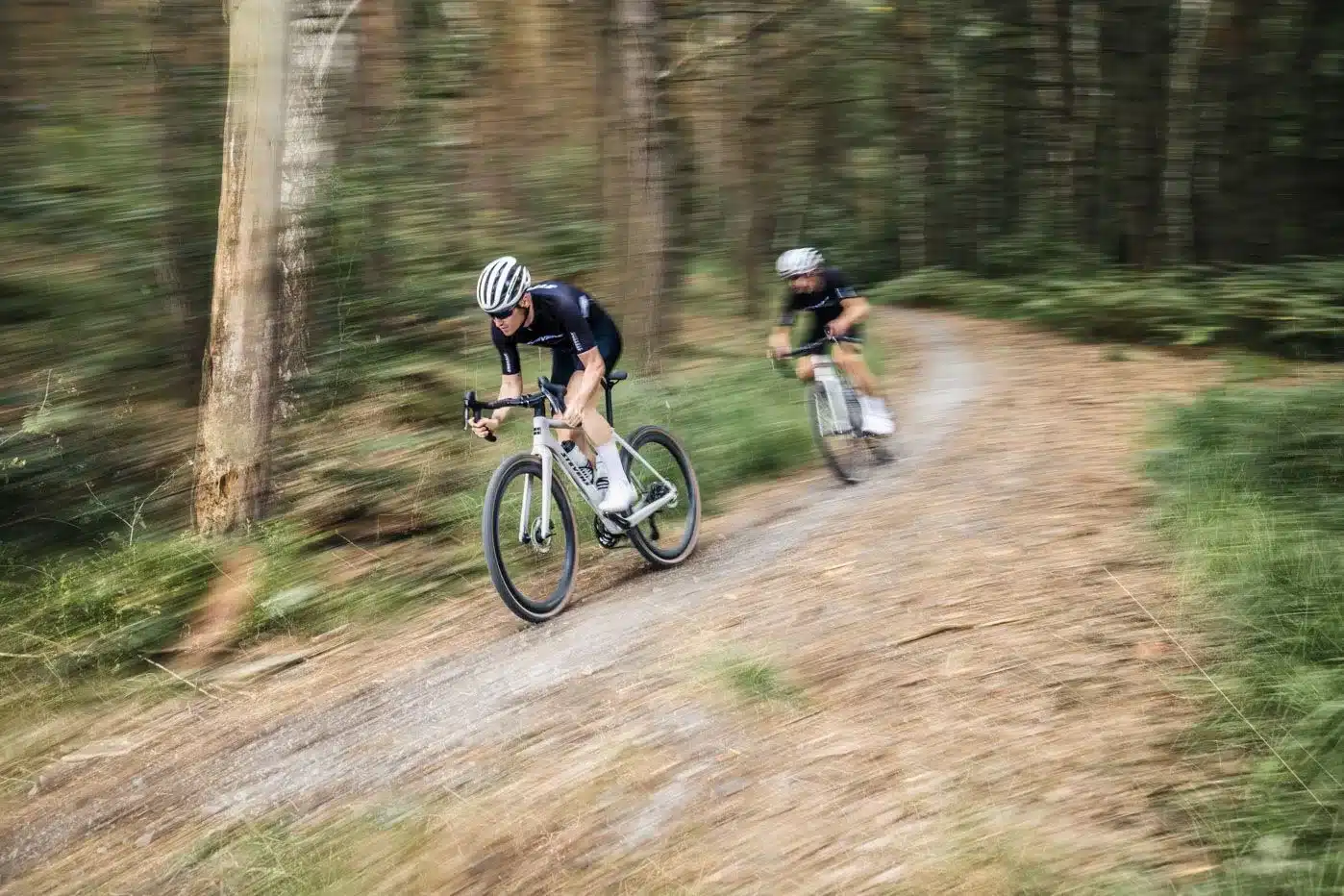 Ein Gravelbiker fährt auf einem Stevens Camino RS Pro Di2-Fahrrad einen Waldweg entlang.