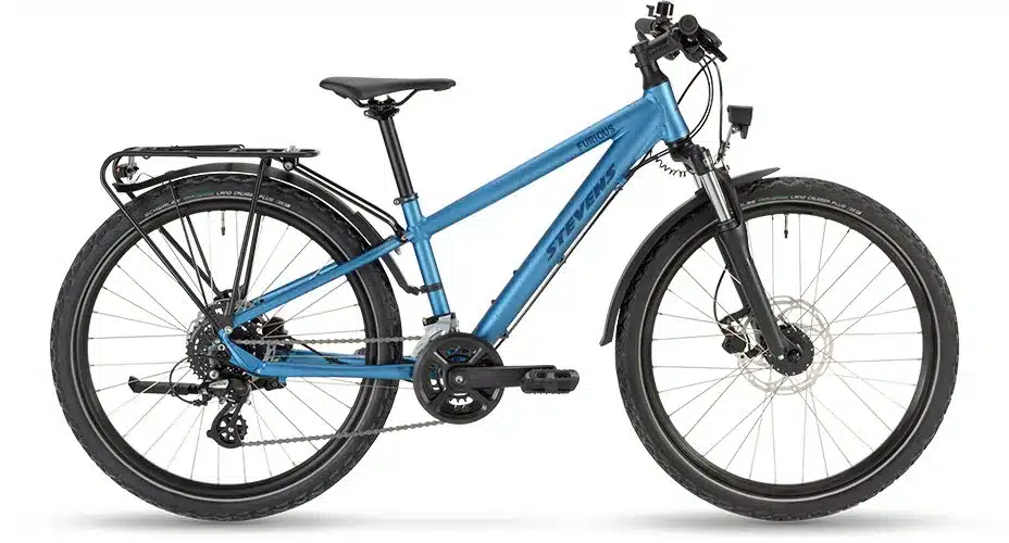 Ein blaues Stevens Furious Tour 24 Junior-Fahrrad mit Gepäckträger, Schutzblechen und Federgabel, isoliert auf weißem Hintergrund.