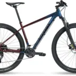 Seitenansicht eines Stevens Taniwha Mountainbikes mit blau-rotem Rahmen, 29-Zoll-Rädern und Federgabel.