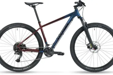 Seitenansicht eines Stevens Taniwha Mountainbikes mit blau-rotem Rahmen, 29-Zoll-Rädern und Federgabel.