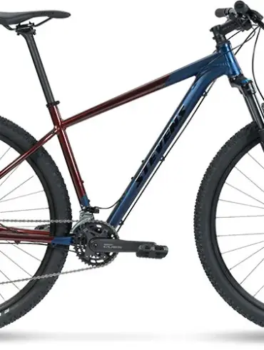 Seitenansicht eines Stevens Taniwha Mountainbikes mit blau-rotem Rahmen, 29-Zoll-Rädern und Federgabel.