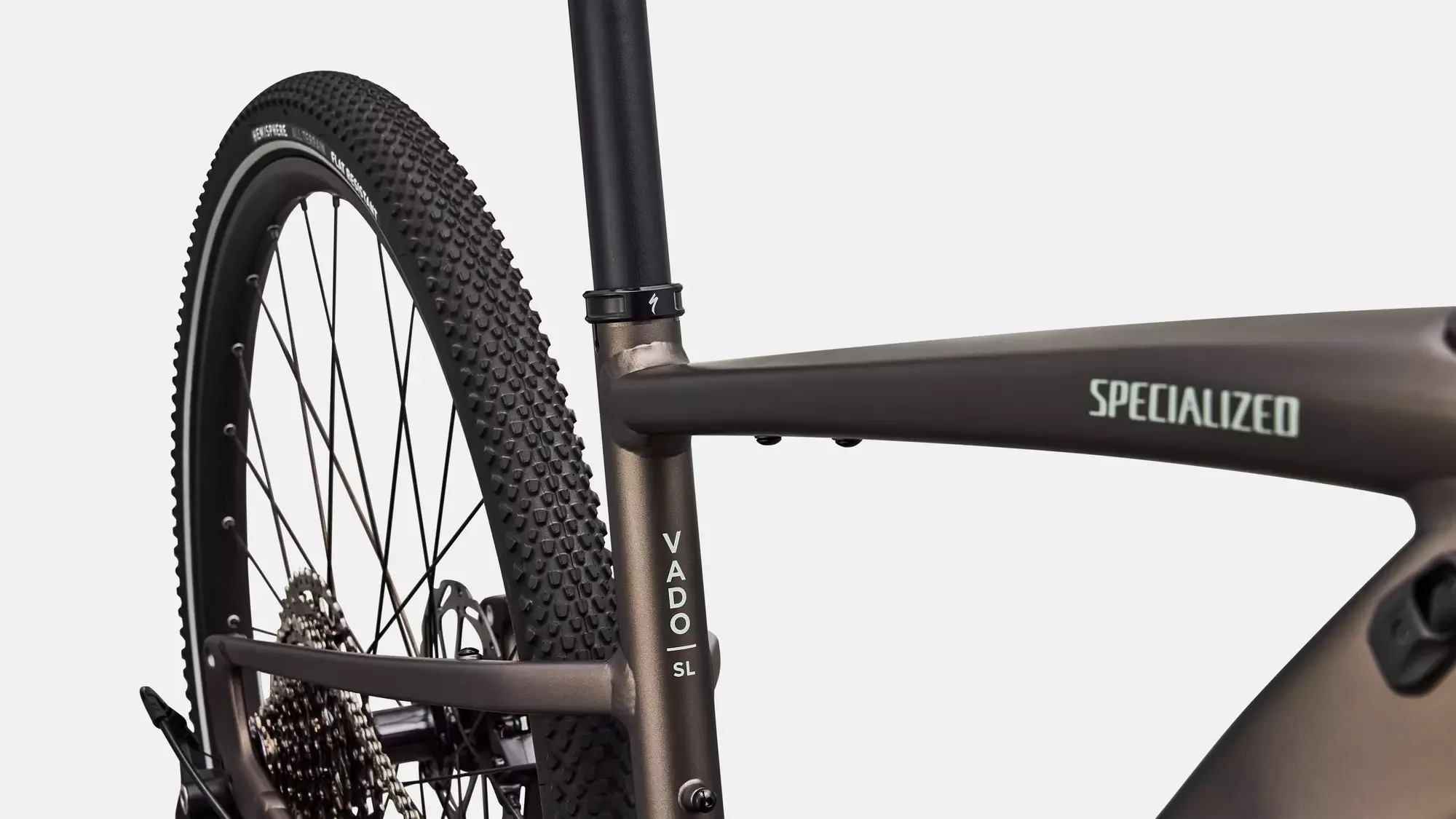 Detailaufnahme eines dunkelgrauen Specialized Turbo Vado SL 2 4.0 E-Bikes, fokussiert auf den Schriftzug 'VADO SL' am Sitzrohr und das grobstollige Hinterreifenprofil.