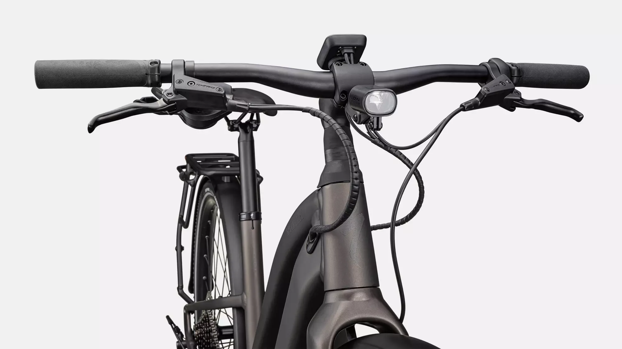 Nahaufnahme des Lenkers eines schwarzen E-Bikes, zeigt Bremsgriffe, Beleuchtung und ein kleines Display