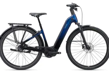 Seitenansicht eines blauen Giant AnyTour E+ 3 E-Bikes mit Gepäckträger, Schutzblechen und Riemenantrieb.