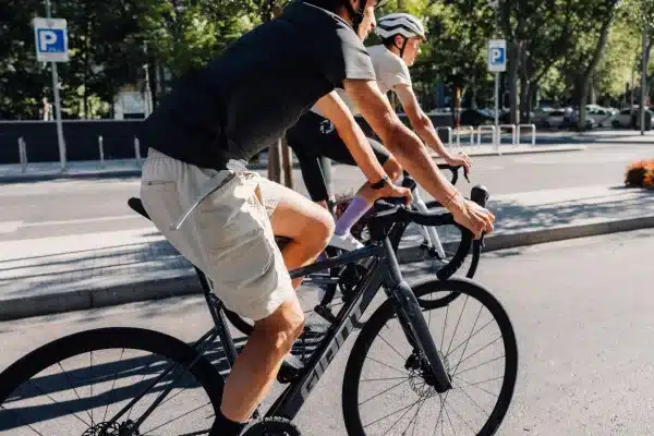 Zwei Personen fahren auf Rennrädern des Modells Giant Contend SL 0 auf einer Straße, eine Person im Vordergrund mit beiger Hose und schwarzem Oberteil, die zweite Person dahinter mit weißem Oberteil.