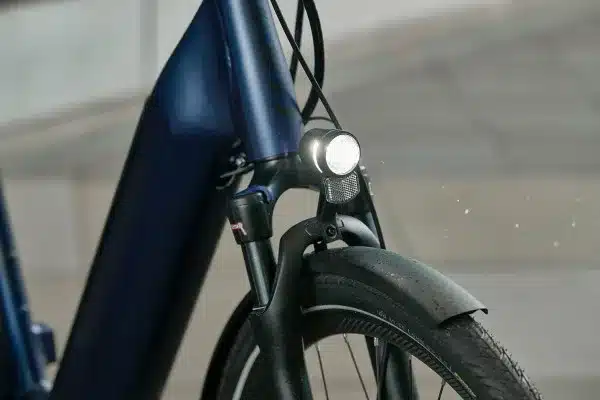 Detailansicht eines dunkelblauen Giant DailyTour E+ 2 GTS E-Bikes mit Fokus auf die Vorderachse, Beleuchtung und Schutzblech.