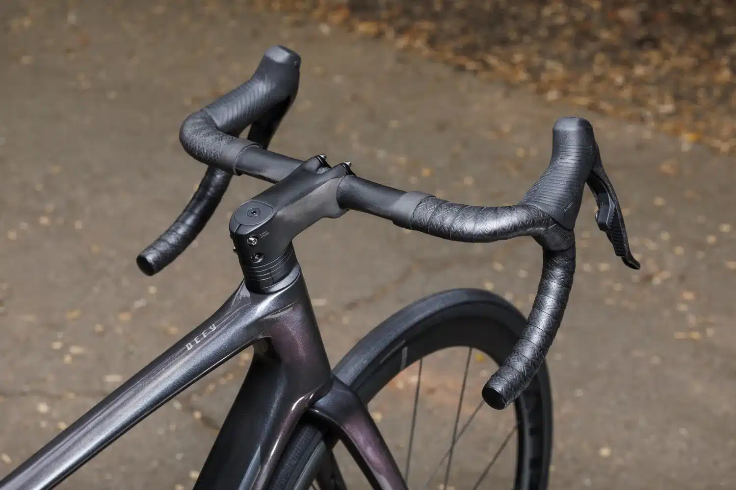 Nahaufnahme des Cockpits eines Giant Defy Advanced SL 0 Rennrads mit dunklem Carbonrahmen, integriertem Vorbau und Lenker mit Lenkerband.
