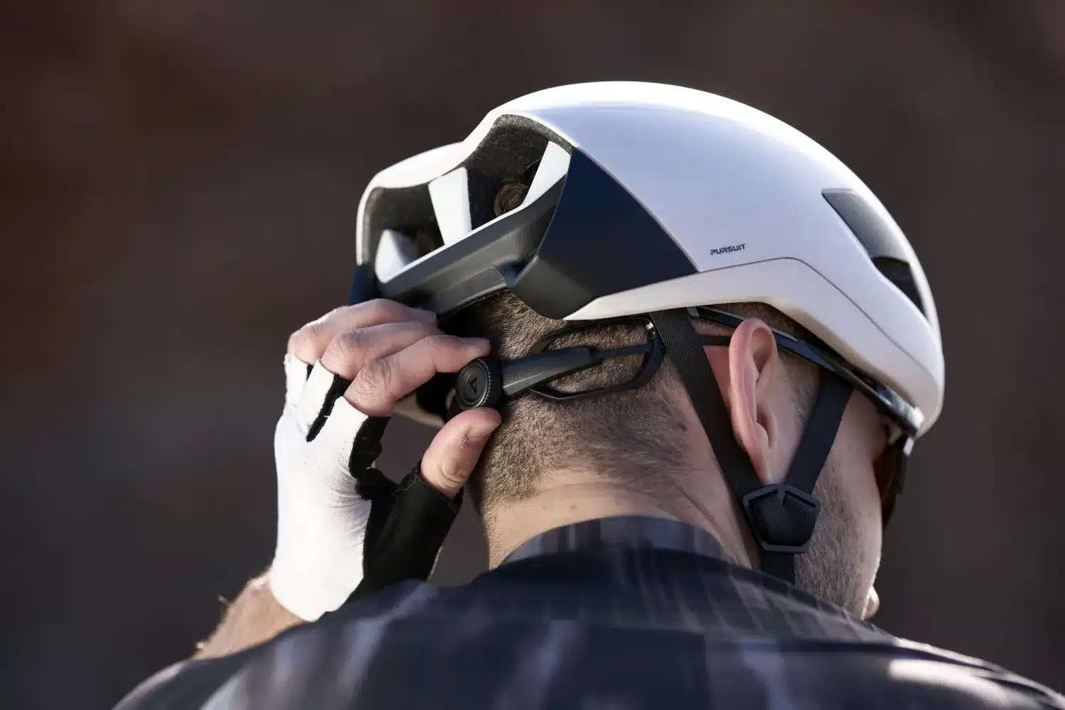 Eine Person stellt den Giant Pursuit Aero Helm 2026 am Hinterkopf ein.