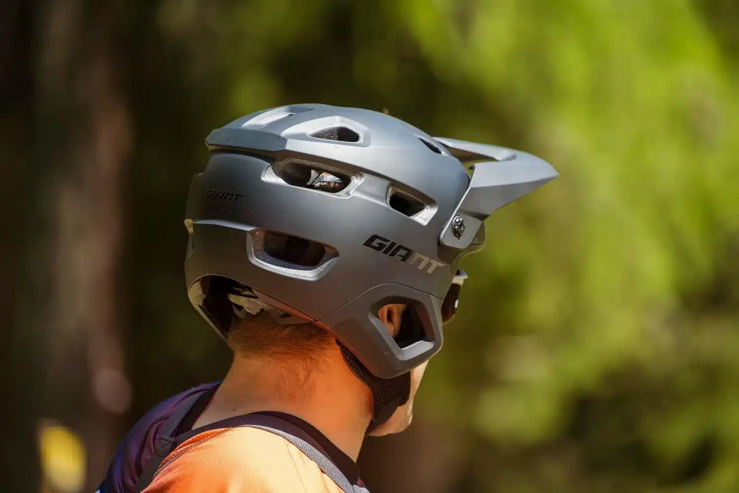Seitenansicht eines schwarzen Giant Realm MIPS Fullface-Helms, der von einem Mountainbiker im Gelände getragen wird.