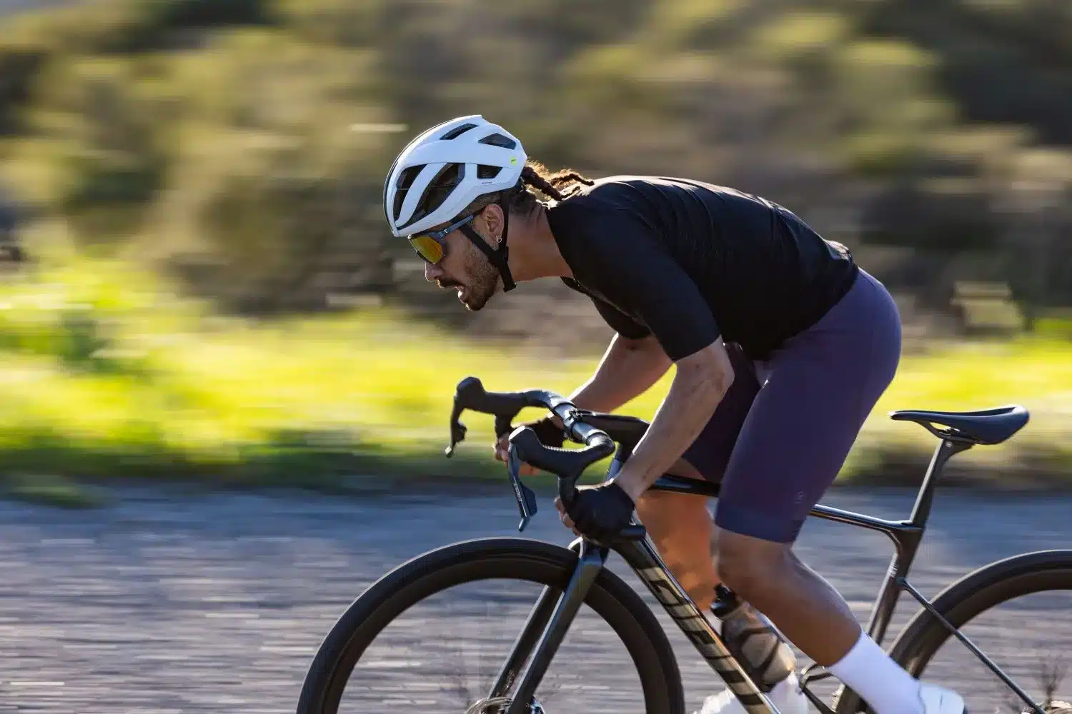Rennradfahrer auf einem Fahrrad mit einem weißen Rennradhelm.