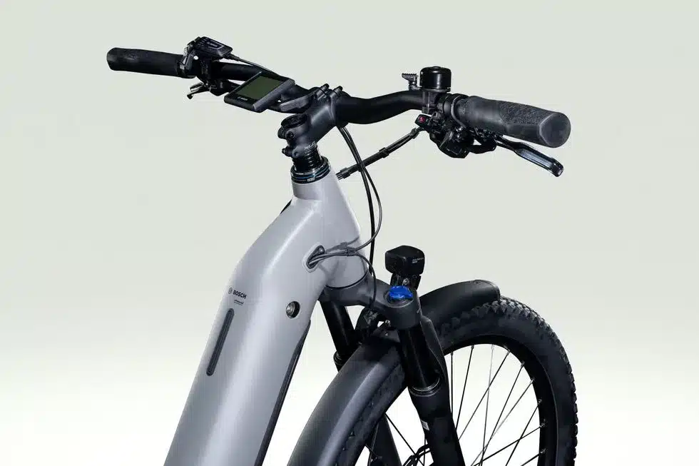 Nahaufnahme des Cockpits und des Vorderrads eines Lapierre E-Explorer 5.5 Low E-Trekkingrads, mit Bosch-Display und SR Suntour Federgabel.