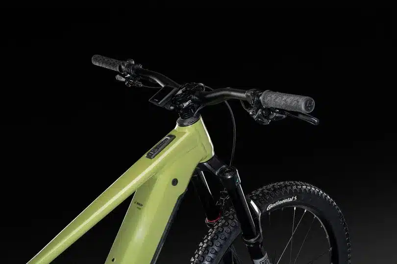 Nahaufnahme des Cockpits eines grünen Lapierre Overvolt AM AL 5.8 E-Mountainbikes mit breitem Lenker, Display und Federgabel.