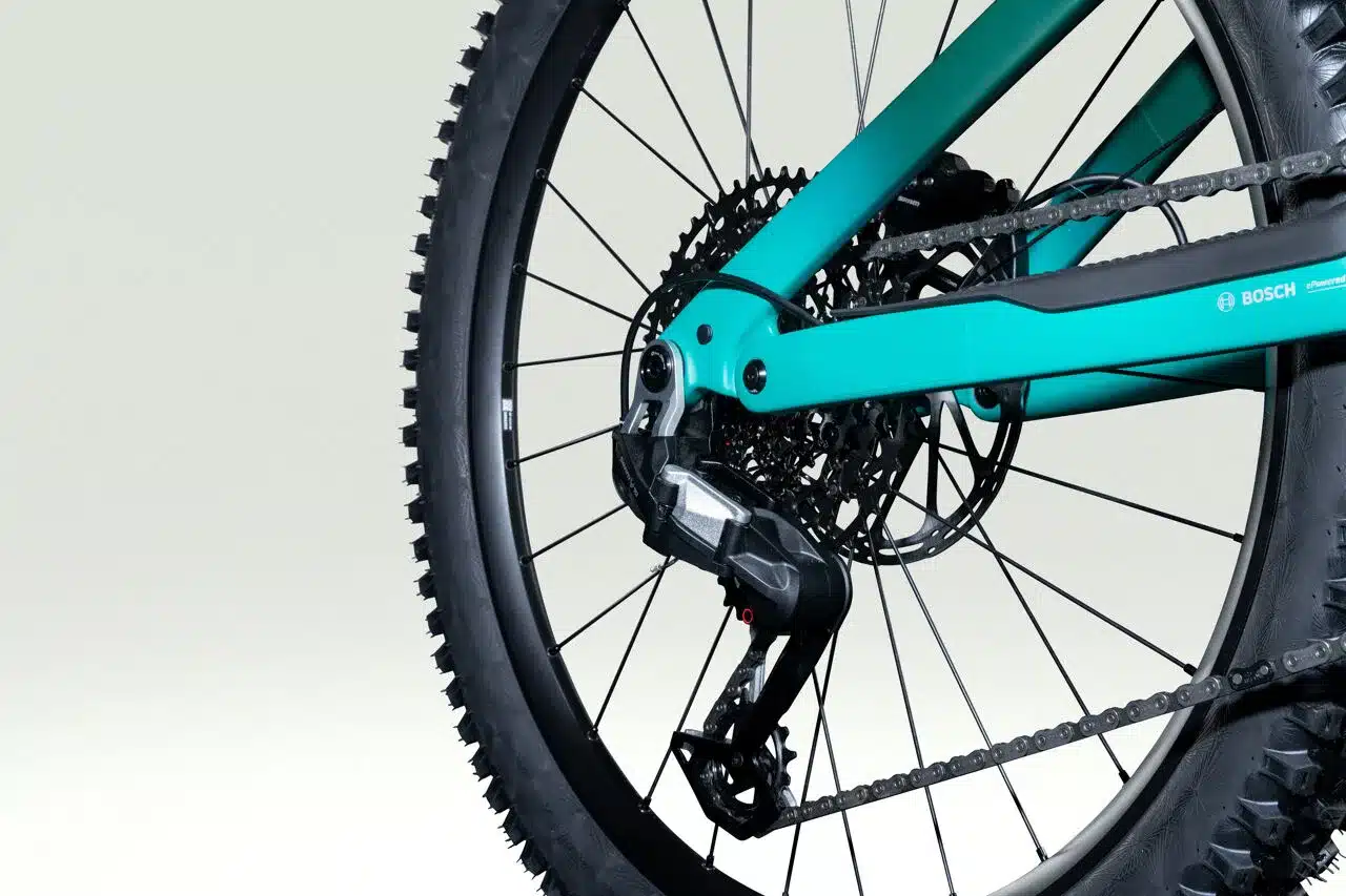 Nahaufnahme des Hinterrads eines turquoise E-Mountainbikes mit Fokus auf die SRAM 12-Gang-Schaltung, die Kassette, die Kette und die Bosch eBike Motorisierung.