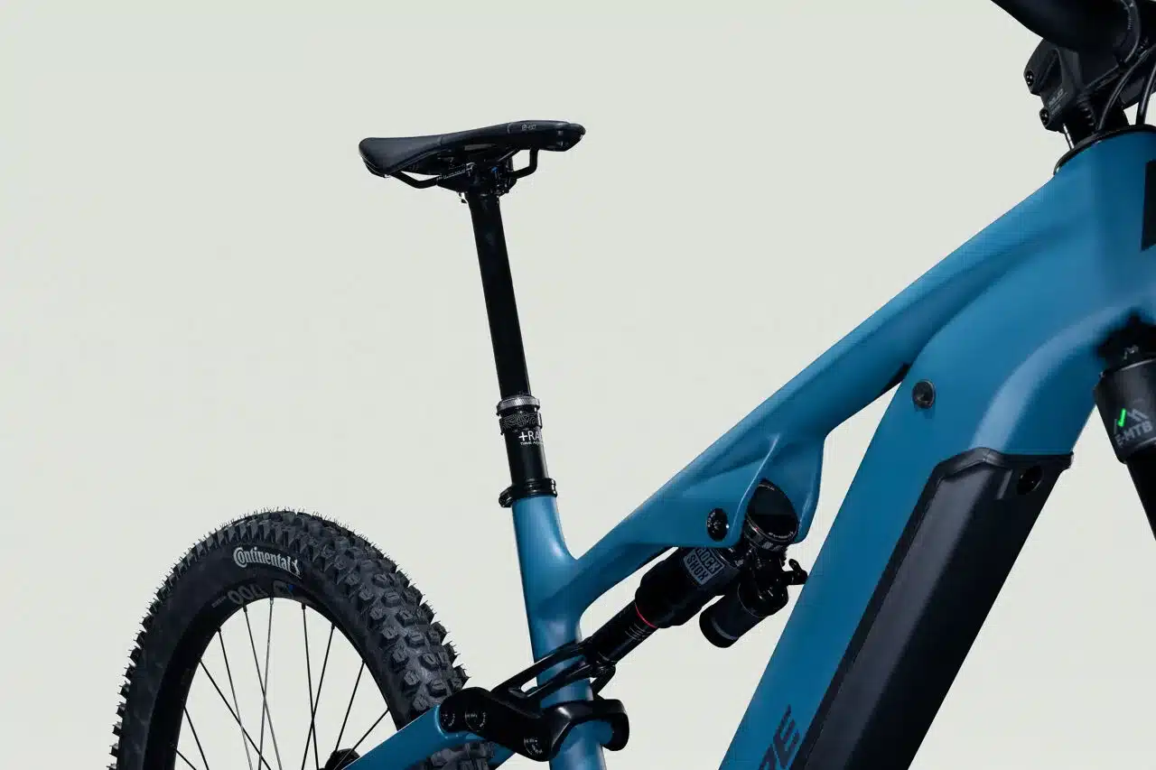 Blaues E-Mountainbike Overvolt AM CF 7.8 im Detail, zeigt den Dämpfer und den Carbonrahmen.