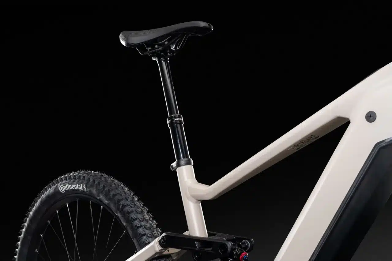 Nahaufnahme des Lapierre Overvolt TR 6.8 E-Mountainbikes, Fokus auf den Sattel, die verstellbare Sattelstütze, das Hinterrad mit Continental-Reifen und den cremefarbenen Rahmen.