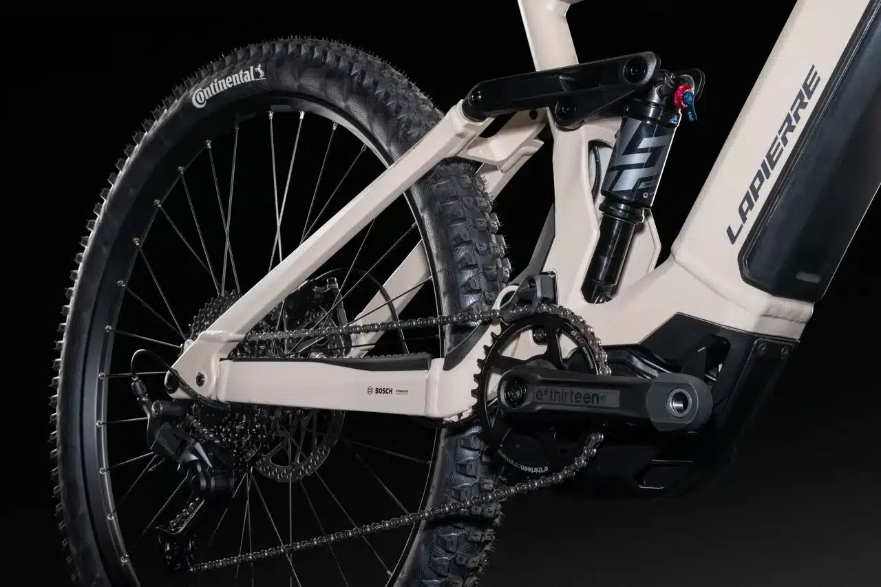Detailansicht des Hinterrades, Kette, Schaltung, Dämpfer und des Bosch Motors eines Lapierre Overvolt TR 6.8 E-Mountainbikes in Beigeton.