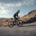 Ein Radfahrer fährt mit einem Lapierre Pulsium 5.0 Endurance-Rennrad eine Bergstraße in bergiger, ländlicher Umgebung.
