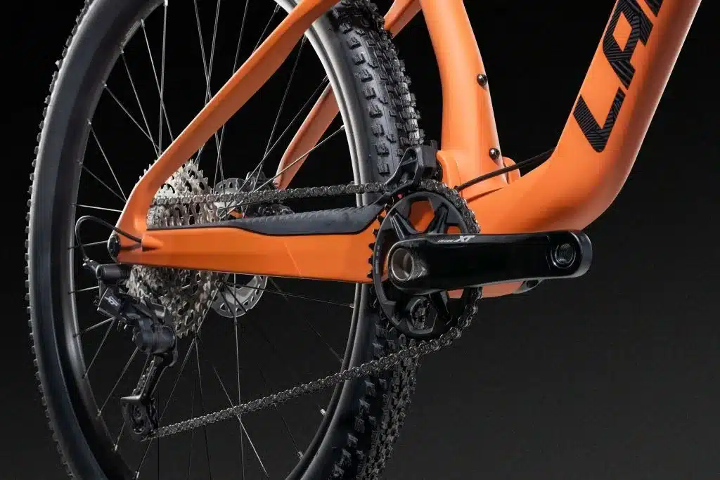 Nahaufnahme des Antriebsstrangs eines orangefarbenen Lapierre XRM 6.9 Mountainbikes mit Fokus auf Schaltwerk, Kassette und Kurbelgarnitur.
