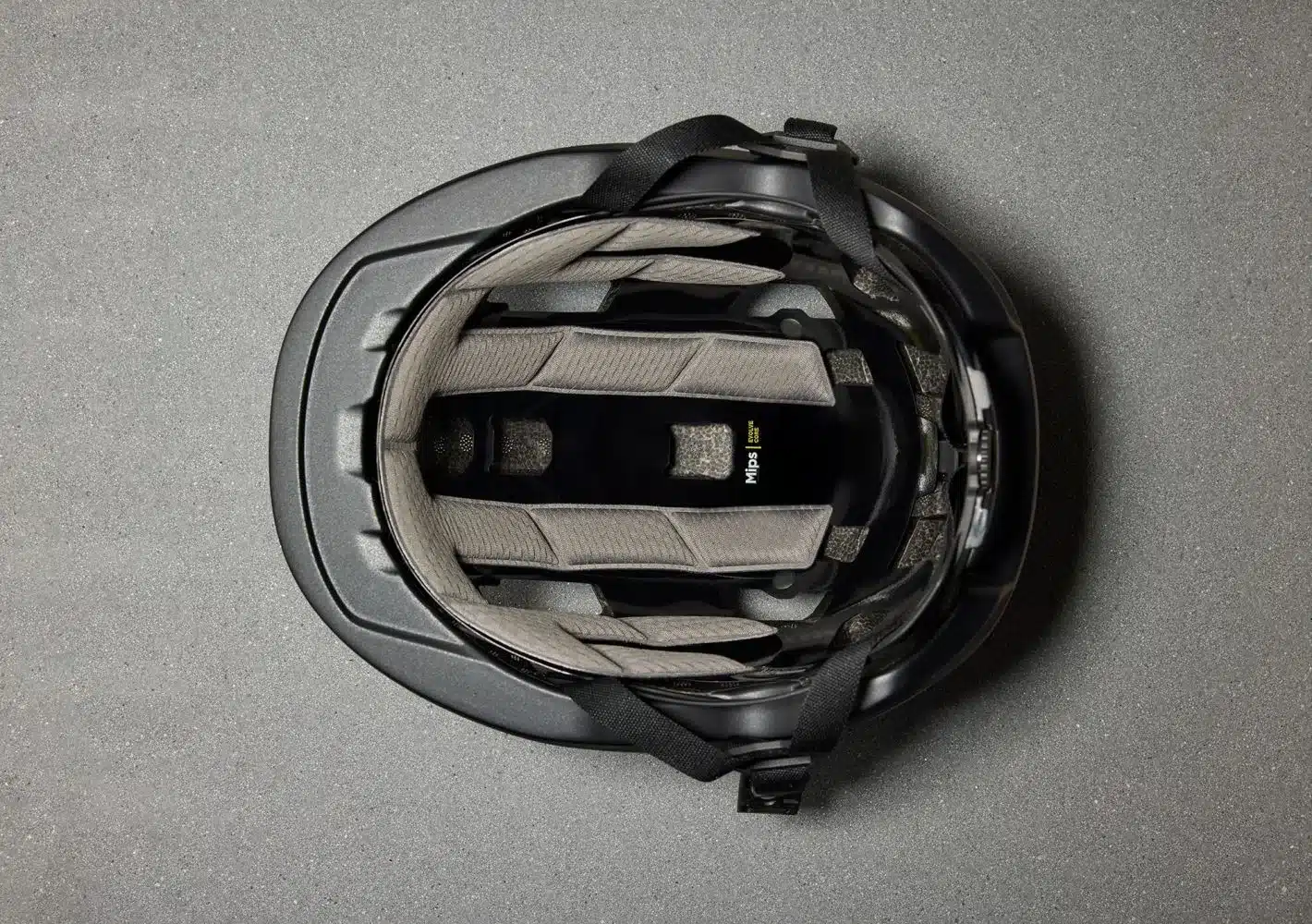 Oben-Draufsicht auf die Innenseite eines schwarzen Fahrradhelms, der das Mips-System und die Polsterung zeigt.