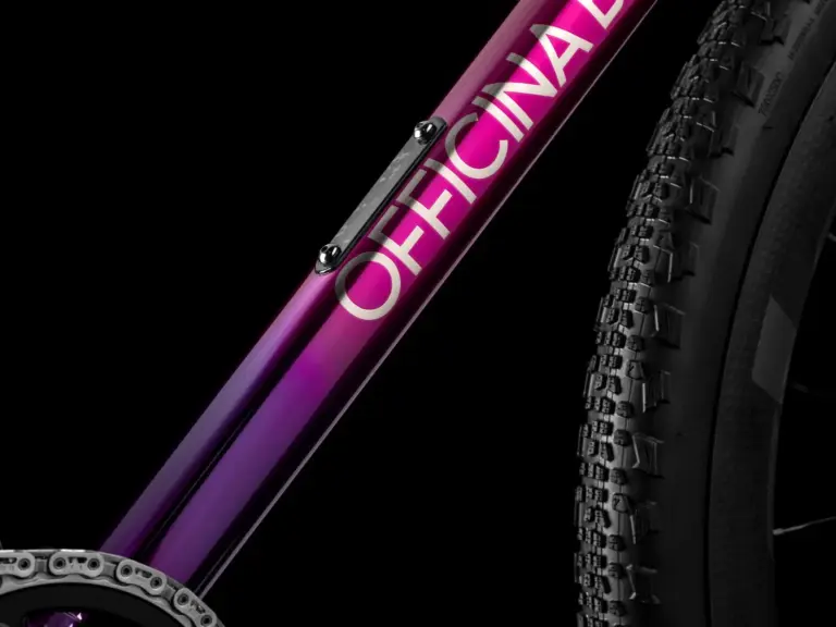 Detailaufnahme eines Fahrradrahmens mit dem Schriftzug OFFICINA in weiß und einem Farbverlauf von Lila zu Pink.