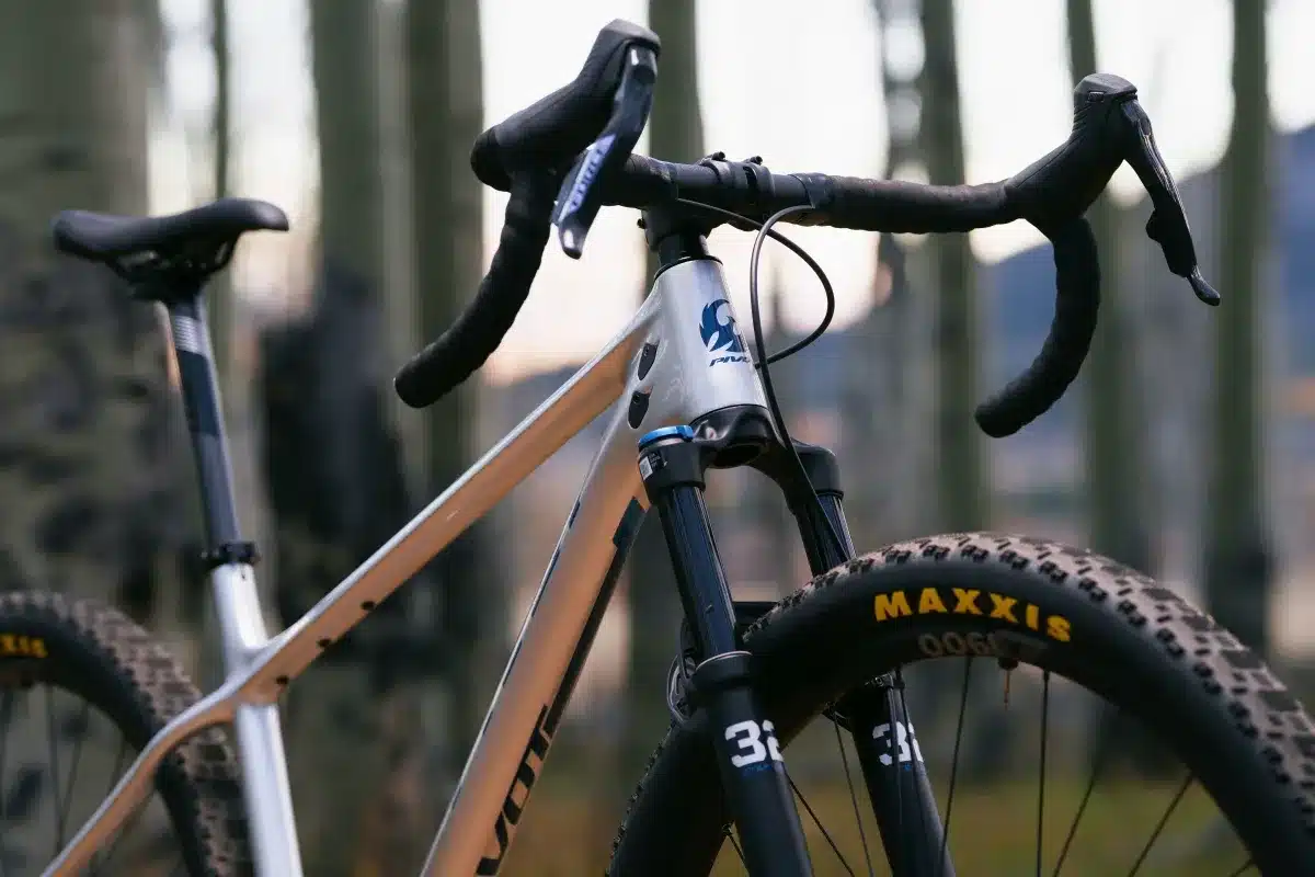 Nahaufnahme des silbernen Pivot LES SL Drop Bar Fahrradrahmens mit Dropbar-Lenker, breiter Maxxis-Reifen und FOX Gabel.