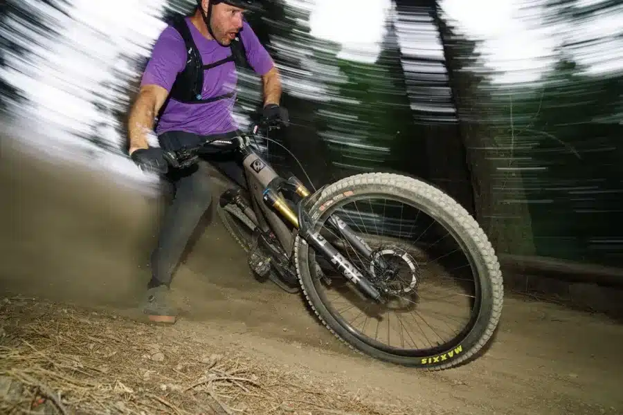 Ein Mountainbiker fährt ein Specialized E-Mountainbike auf einem staubigen Trail mit Bäumen im Hintergrund.
