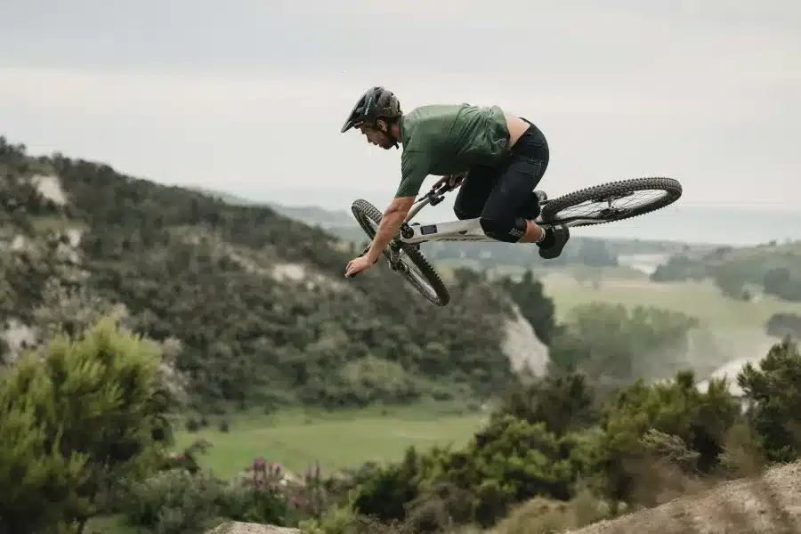 Ein Mountainbiker springt mit dem Pivot Shuttle LT über eine Anhöhe, während er in der Luft ist.