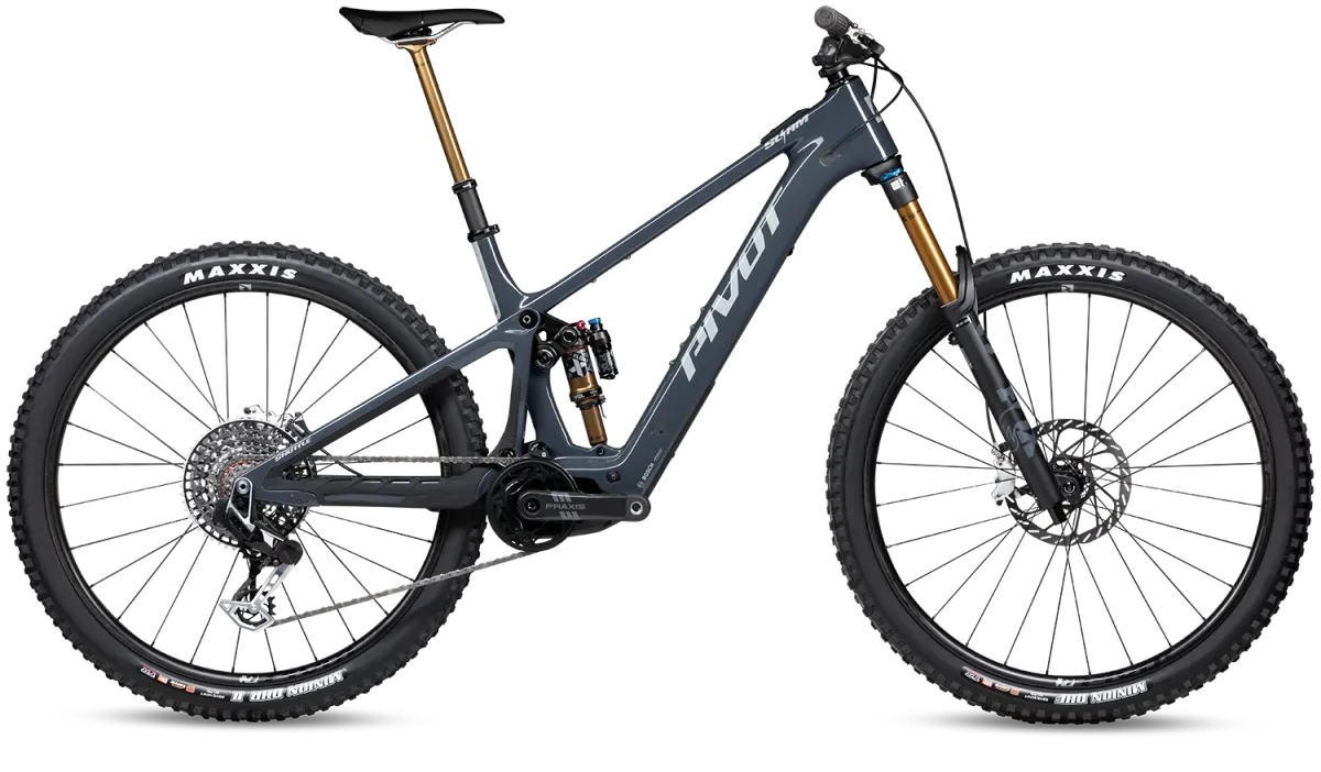 Seitenansicht des grauen Pivot Shuttle SL/AM E-Mountainbikes, das auf einem schwarzen Hintergrund steht. Das Fahrrad ist mit Maxxis-Reifen, SRAM-Schaltung und FOX-Federung ausgestattet. Der Bosch-Motor und der Akku sind integriert.