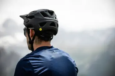 Rückansicht eines Mannes, der einen schwarzen Mountainbike-Helm mit Mips-Aufkleber trägt.