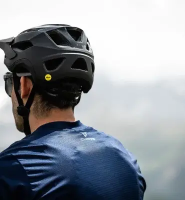 Rückansicht eines Mannes, der einen schwarzen Mountainbike-Helm mit Mips-Aufkleber trägt.