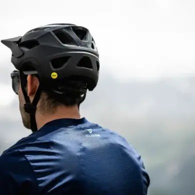 Rückansicht eines Mannes, der einen schwarzen Mountainbike-Helm mit Mips-Aufkleber trägt.